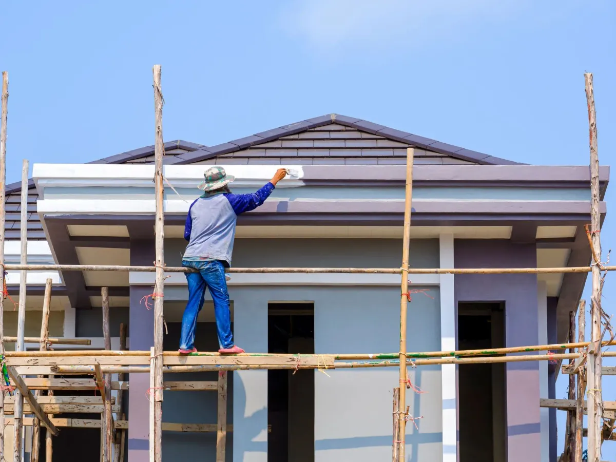 A painter on scaffolding painting the eaves of a building — commercial exterior painting in New Bedford, MA