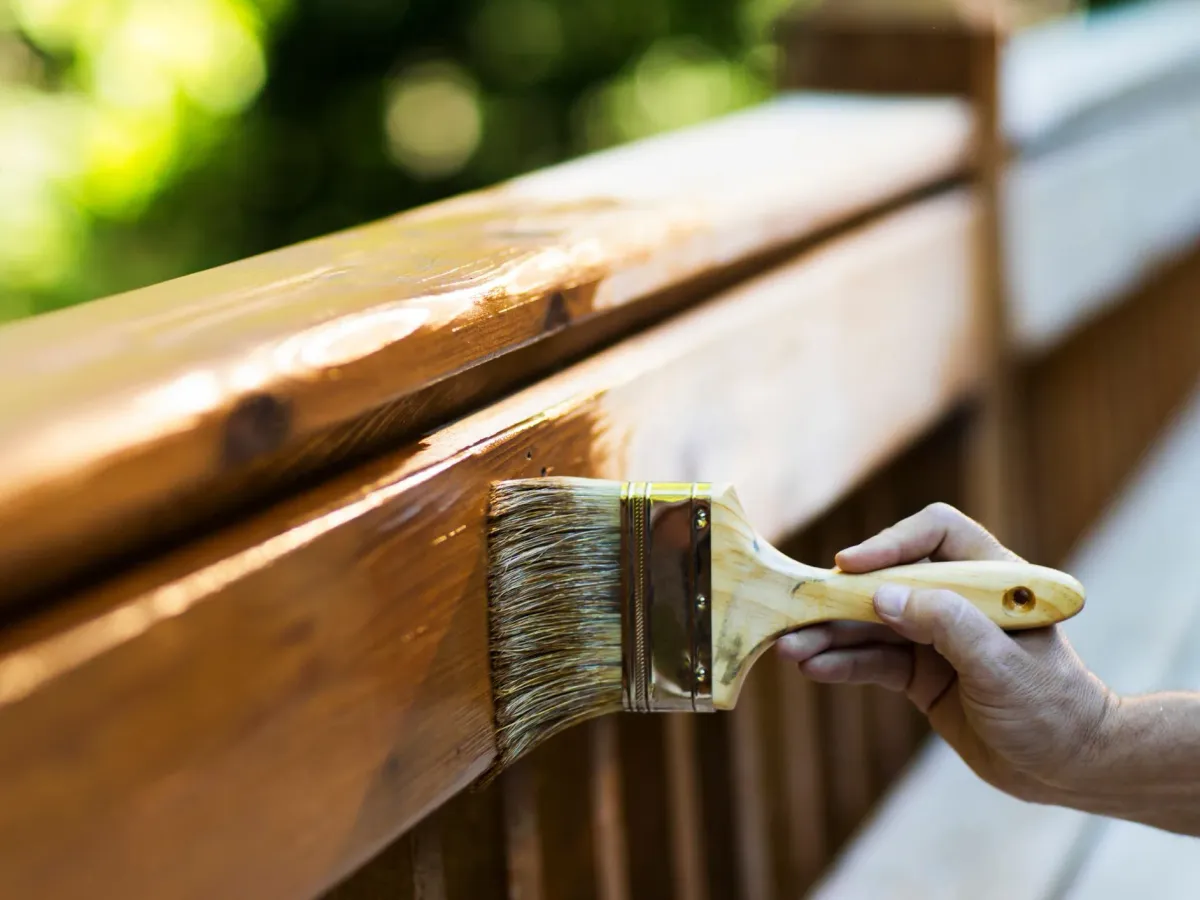 A brush staining a wooden deck railing — deck and porch staining in New Bedford, MA