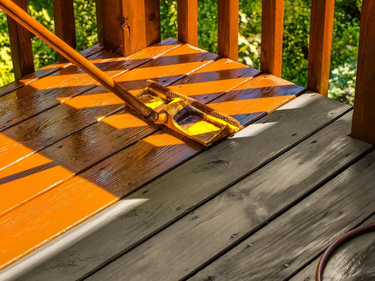 Stain going on with a pad over clean, weathered deck boards — deck staining in New Bedford, MA