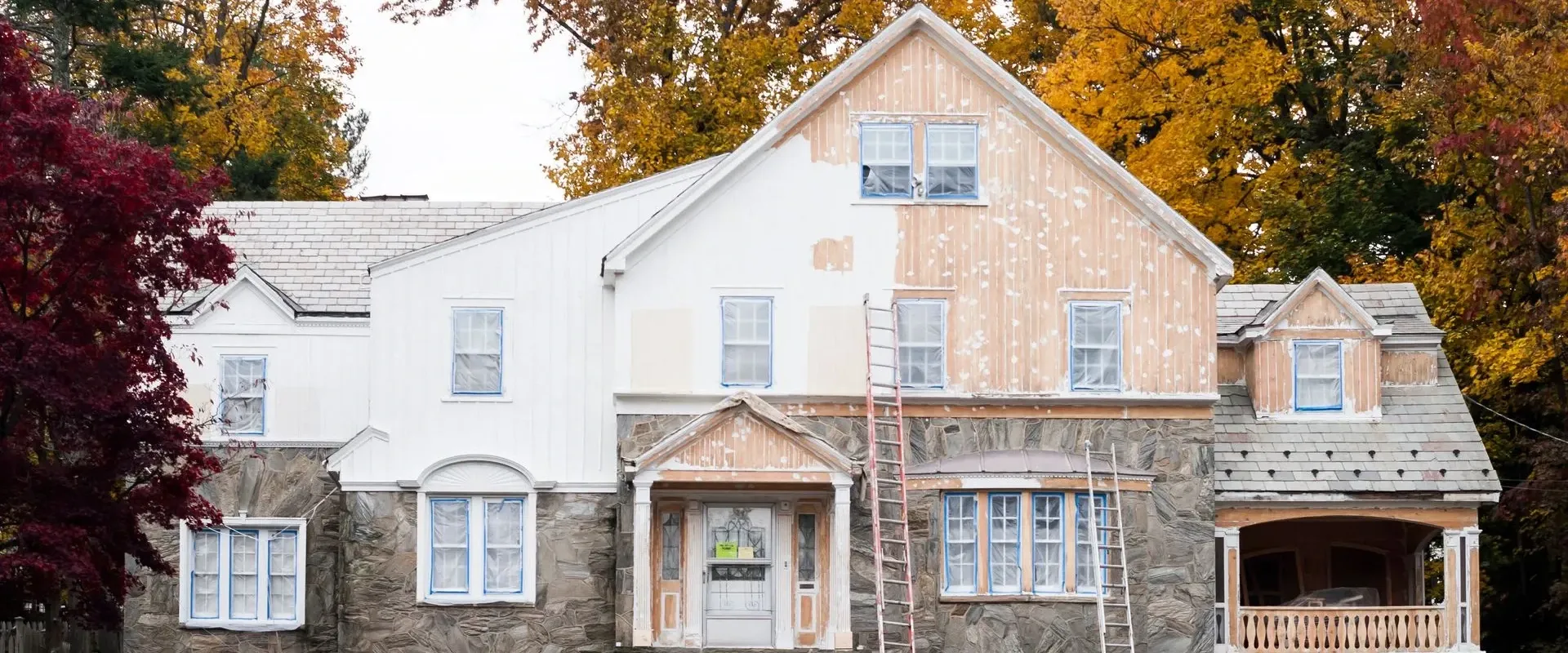 A large older house partway through exterior work, ladders against its walls — house painting in New Bedford, MA