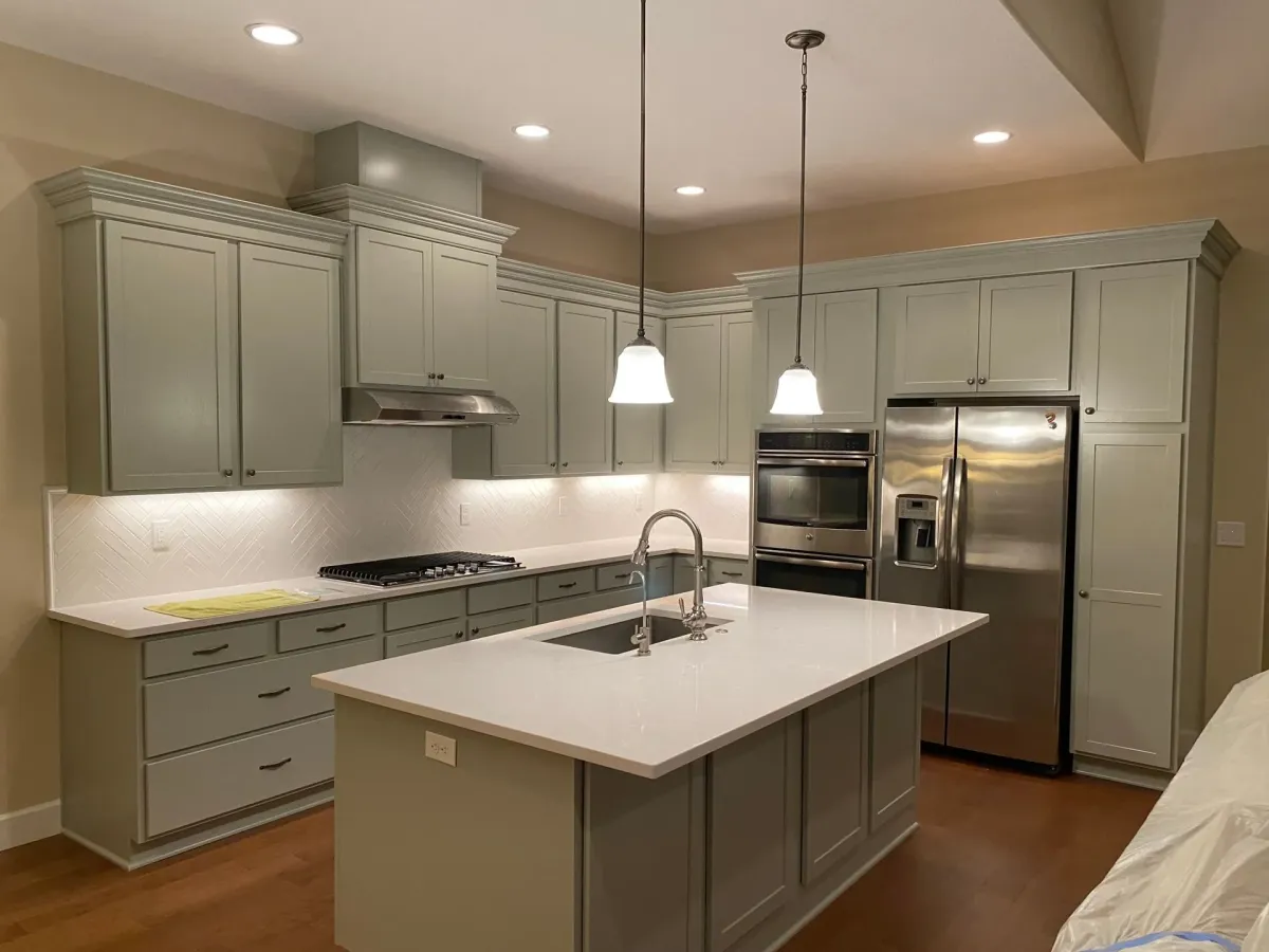 Sage-green painted kitchen cabinets under pendant lights — cabinet painting in New Bedford, MA