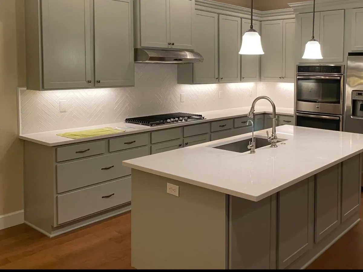 A kitchen with a wood-look floor and sage-green cabinets — flooring in New Bedford, MA