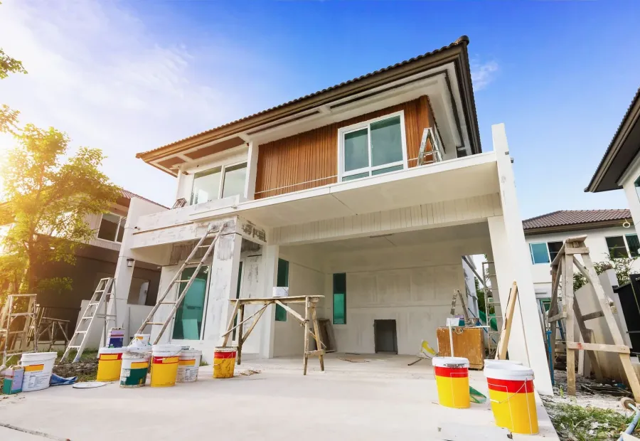 A two-storey house during renovation, with rendered walls, ladders and paint buckets — masonry in New Bedford, MA