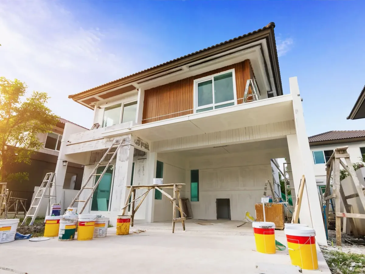 A two-storey house during renovation, with rendered walls, ladders and scaffolding — masonry in New Bedford, MA