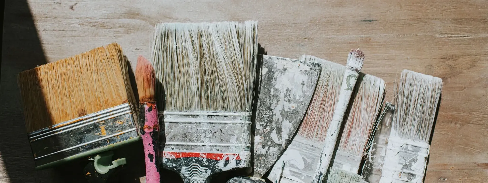 Well-used paint brushes laid side by side — Yes We Can Painting in New Bedford, MA