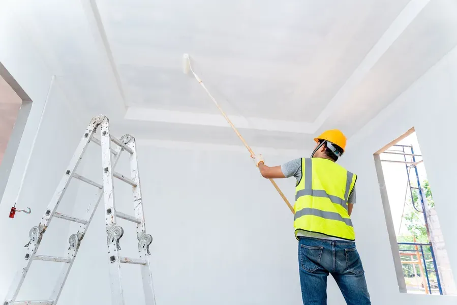 A worker rolling paint onto a smooth new ceiling — sheetrock and taping in New Bedford, MA
