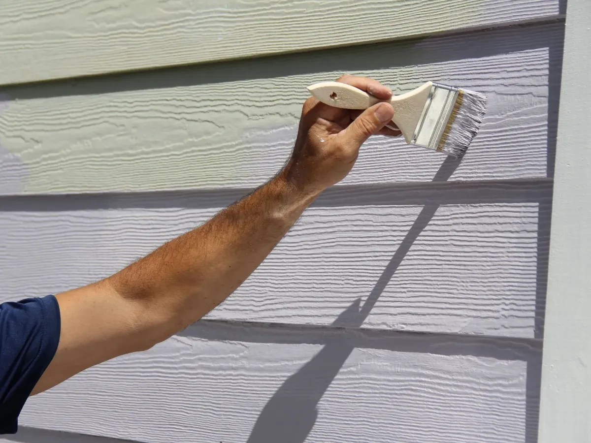 Lap siding being repainted by brush, the new coat beside the old — exterior painting in New Bedford, MA
