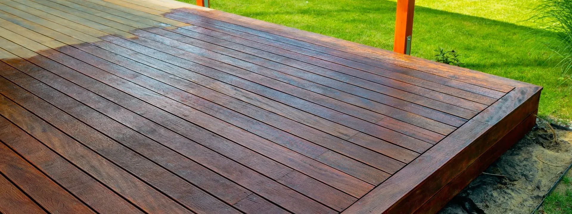 A freshly stained wooden deck on a lawn — deck staining and sealing in New Bedford, MA