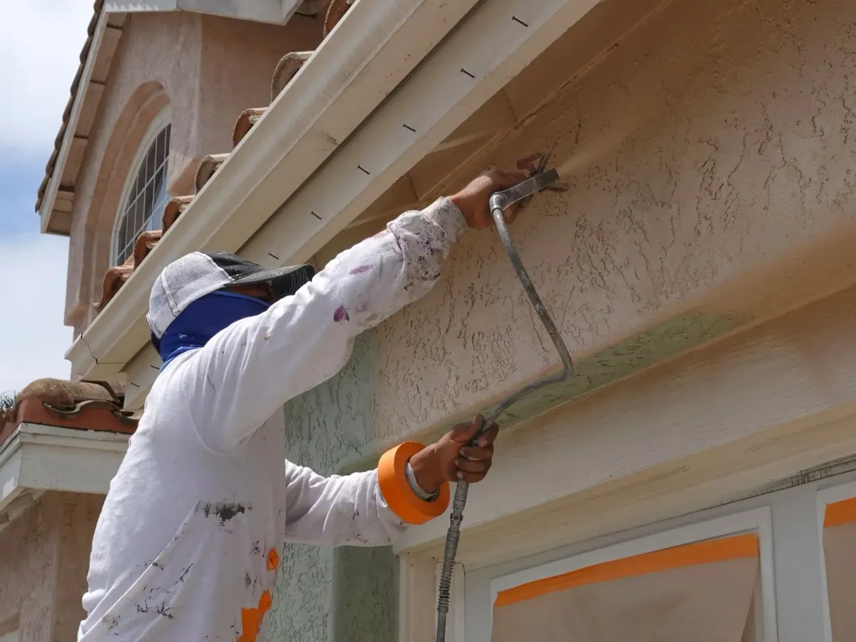 A painter spraying a textured stucco wall — masonry and painting in New Bedford, MA