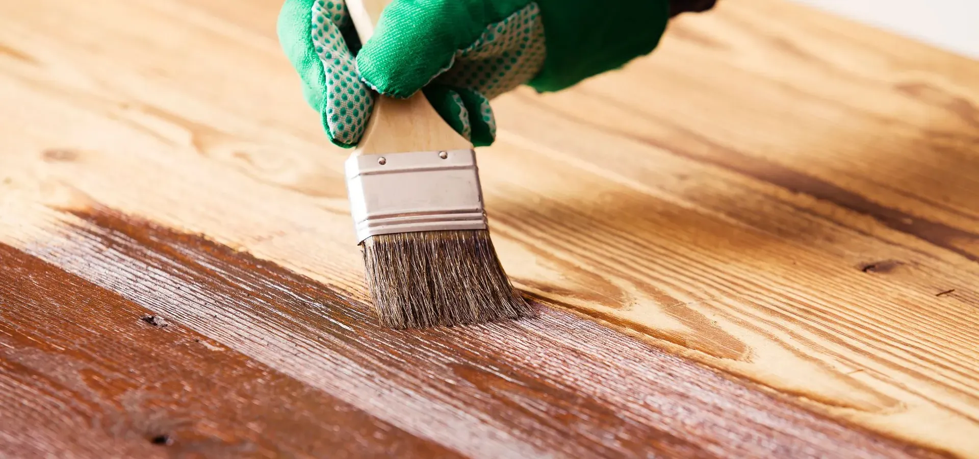 A gloved hand brushing finish onto wooden boards — flooring in New Bedford, MA