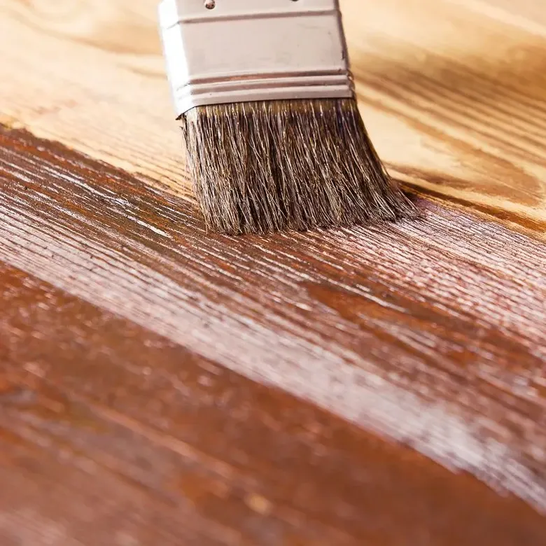 A brush spreading stain along a wooden board, close up — painting and staining in New Bedford, MA
